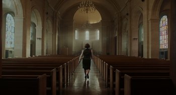 Movie still from “Golda” (2023), directed by Guy Nattiv – A woman walking down the aisle of a church; Extreme Wide shot, Low angle