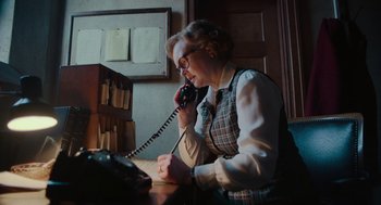 Movie still from “Golda” (2023), directed by Guy Nattiv – An older woman talking on a phone while sitting at a desk; Medium shot, Low angle