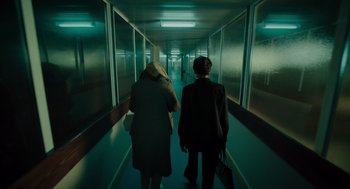Movie still from “Golda” (2023), directed by Guy Nattiv – Two people are walking down a long hallway; Wide shot, High angle