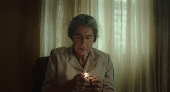 Movie still from “Golda” (2023), directed by Guy Nattiv – An older woman lighting a cigarette in a room; Close Up shot, High angle