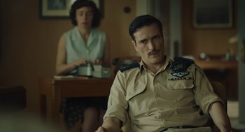 Movie still from “Golda” (2023), directed by Guy Nattiv – A man and a woman sitting at a table in a room; Medium shot, Low angle