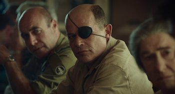 Movie still from “Golda” (2023), directed by Guy Nattiv – A man with a bandaged eye sitting next to another man; Close Up shot, Over the shoulder angle