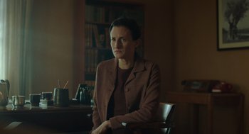 Movie still from “Golda” (2023), directed by Guy Nattiv – A woman sitting in front of a desk in a room; Medium shot, Low angle