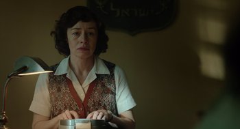 Movie still from “Golda” (2023), directed by Guy Nattiv – A woman holding a metal container in a room; Medium shot, Low angle