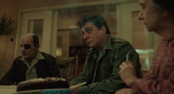 Movie still from “Golda” (2023), directed by Guy Nattiv – A man sitting at a table with food in front of him; Medium shot, Over the shoulder angle