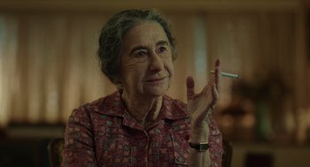 Movie still from “Golda” (2023), directed by Guy Nattiv – An older woman is holding a cigarette in her hand; Close Up shot, Over the shoulder angle