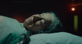 Movie still from “Golda” (2023), directed by Guy Nattiv – An older woman laying down on a bed with her eyes closed; Close Up shot, High angle