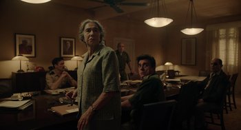 Movie still from “Golda” (2023), directed by Guy Nattiv – A man and a woman are standing in front of a table; Medium shot, Low angle
