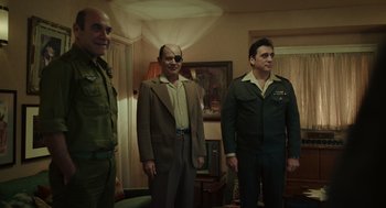 Movie still from “Golda” (2023), directed by Guy Nattiv – A group of men standing next to each other in a living room; Medium shot, Low angle