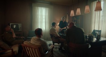 Movie still from “Golda” (2023), directed by Guy Nattiv – A group of people sitting in a living room; Wide shot, Low angle