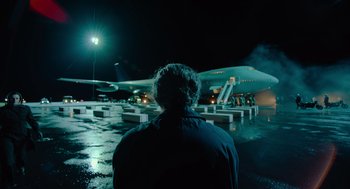Movie still from “Golda” (2023), directed by Guy Nattiv – A man standing in front of an airplane at an airport; Wide shot, Low angle