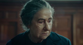 Movie still from “Golda” (2023), directed by Guy Nattiv – An older woman with a sad look on her face; Close Up shot, Over the shoulder angle