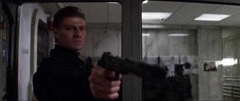 Movie still from “GoldenEye” (1995), directed by Martin Campbell – A man holding a gun while standing in front of a mirror; Close Up shot, Low angle