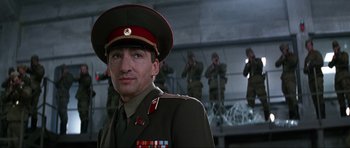 Movie still from “GoldenEye” (1995), directed by Martin Campbell – A man in a military uniform is standing in front of a group of soldiers; Close Up shot, Low angle
