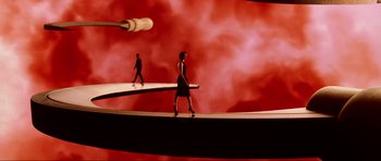 Movie still from “GoldenEye” (1995), directed by Martin Campbell – A woman walking across a bridge while a man is walking across the bridge; Extreme Wide shot, High angle