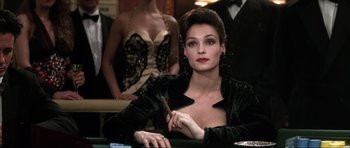 Movie still from “GoldenEye” (1995), directed by Martin Campbell – A woman sitting at a table with a cigarette in her hand; Close Up shot, Over the shoulder angle