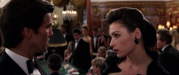 Movie still from “GoldenEye” (1995), directed by Martin Campbell – A man and a woman in a crowd of people in a room; Close Up shot, Over the shoulder angle