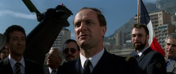 Movie still from “GoldenEye” (1995), directed by Martin Campbell – A man in a black suit and a black tie; Close Up shot, Low angle