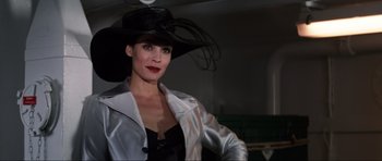 Movie still from “GoldenEye” (1995), directed by Martin Campbell – A woman wearing a black hat and a silver jacket; Close Up shot, Low angle
