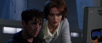 Movie still from “GoldenEye” (1995), directed by Martin Campbell – A man and a woman pose for a picture; Close Up shot, Low angle