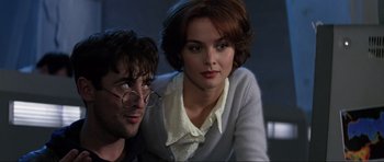 Movie still from “GoldenEye” (1995), directed by Martin Campbell – A woman sitting next to a man with a pair of eyeglasses; Close Up shot, Low angle