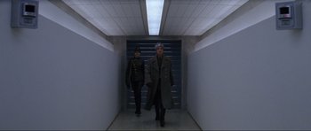 Movie still from “GoldenEye” (1995), directed by Martin Campbell – Two people walking down a hallway in a building; Wide shot, Low angle