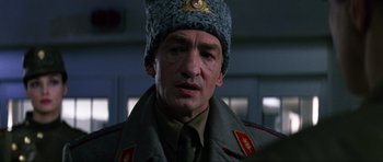 Movie still from “GoldenEye” (1995), directed by Martin Campbell – A person wearing a uniform and wearing a hat; Close Up shot, Low angle