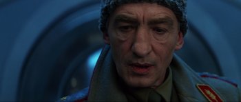 Movie still from “GoldenEye” (1995), directed by Martin Campbell – A person wearing a hat and a scarf; Close Up shot, Low angle