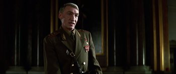 Movie still from “GoldenEye” (1995), directed by Martin Campbell – A man in a military uniform standing in front of a wall; Close Up shot, Low angle