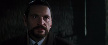 Movie still from “GoldenEye” (1995), directed by Martin Campbell – A person wearing a suit and tie; Close Up shot, Low angle