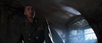 Movie still from “GoldenEye” (1995), directed by Martin Campbell – A man in a military uniform standing in a room; Close Up shot, Low angle