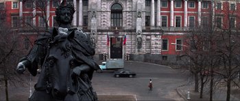 Movie still from “GoldenEye” (1995), directed by Martin Campbell – A street scene with a statue in front of a large building; Extreme Wide shot, Low angle