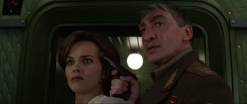 Movie still from “GoldenEye” (1995), directed by Martin Campbell – A man holding a gun next to a woman; Close Up shot, Low angle