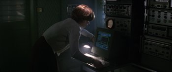 Movie still from “GoldenEye” (1995), directed by Martin Campbell – A woman using a computer in a dark room; Medium shot, High angle
