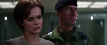 Movie still from “GoldenEye” (1995), directed by Martin Campbell – A woman and a man standing next to each other; Close Up shot, Over the shoulder angle
