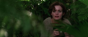 Movie still from “GoldenEye” (1995), directed by Martin Campbell – A woman in the woods looking at the camera; Close Up shot, Low angle