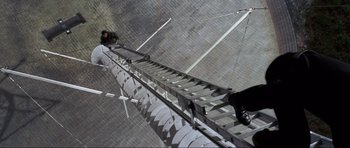 Movie still from “GoldenEye” (1995), directed by Martin Campbell – A man is climbing up a metal ladder; Wide shot, Overhead angle