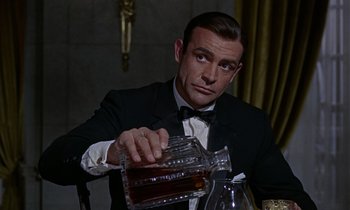 Movie still from “Goldfinger” (1964), directed by Guy Hamilton – A man in a tuxedo pouring a drink into a glass; Close Up shot, Low angle