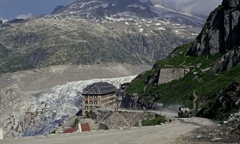Movie still from “Goldfinger” (1964), directed by Guy Hamilton – A building on the side of a road near a mountain; Extreme Wide shot, High angle