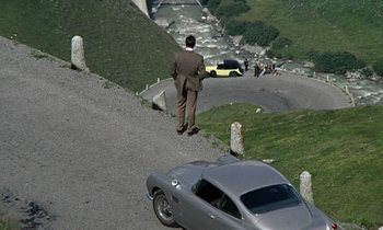 Movie still from “Goldfinger” (1964), directed by Guy Hamilton – A man standing on a hill next to a car; Extreme Wide shot, High angle