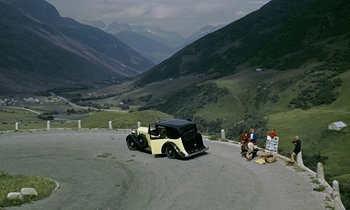 Movie still from “Goldfinger” (1964), directed by Guy Hamilton – An old car is parked on the side of the road; Extreme Wide shot, High angle