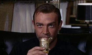 Movie still from “Goldfinger” (1964), directed by Guy Hamilton – A man drinking a drink from a cup; Close Up shot, Low angle