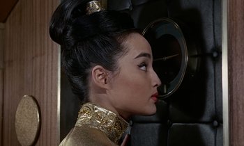 Movie still from “Goldfinger” (1964), directed by Guy Hamilton – A woman in a gold outfit looking to the side; Close Up shot, Over the shoulder angle