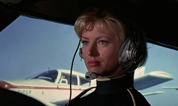 Movie still from “Goldfinger” (1964), directed by Guy Hamilton – A woman with a headset in a helicopter; Close Up shot, Low angle