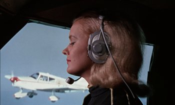 Movie still from “Goldfinger” (1964), directed by Guy Hamilton – A woman wearing a headset in an airplane cockpit; Close Up shot, Low angle