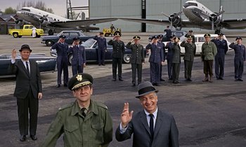 Movie still from “Goldfinger” (1964), directed by Guy Hamilton – A group of men standing next to each other in front of an airplane; Wide shot, High angle