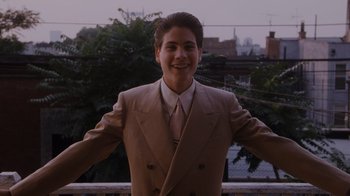 Movie still from “Goodfellas” (1990), directed by Martin Scorsese – A man in a suit and tie standing in front of trees; Medium shot, Low angle
