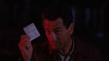Movie still from “Goodfellas” (1990), directed by Martin Scorsese – A man holding a piece of paper up to his face; Close Up shot, Over the shoulder angle