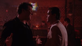 Movie still from “Goodfellas” (1990), directed by Martin Scorsese – Two men are talking in a dark room; Medium shot, Over the shoulder angle