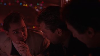 Movie still from “Goodfellas” (1990), directed by Martin Scorsese – A group of people sitting in a room at night; Close Up shot, Over the shoulder angle